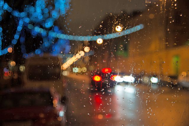Wet car window with the background of night city lights
