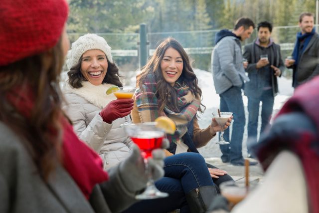 Friends in warm clothing drinking on patio Mit wärmenden und geistvollen Getränken kann die Party auch bei frostigen Temperaturen starten.