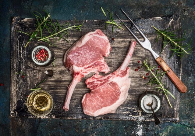 Raw pork cutlet with oil and spices for grill or cooking on rustic background, top view. Porco Iberico French Racks. Iberico Koteletts