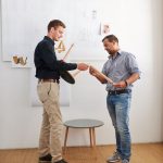 Der schnelle Zusammenbau eines Drei-Bein-Hockers wird von zwei Mitarbeitern überprüft.