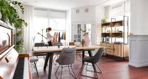 Helle Wände, ein Tisch mit Holzplatte und Sessel im Retro-Design ergeben eine stimmige Einrichtung.