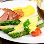 Spargel liebt Silvaner: Der Spargel wird in Karlstadt und Umgebung wie hier im Bild ganz klassisch mit Schinken, Kartoffeln und Sauce Hollandaise serviert, aber auch mit Fisch. Dazu passt jeweils am besten ein fränkischer Silvaner. Foto: djd/Stadt Karlstadt/printemps/Fotolia