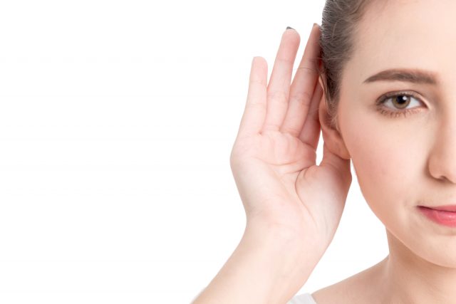 Woman hand on ear listening for quiet sound isolated on white ba Im-Ohr-Hörsysteme