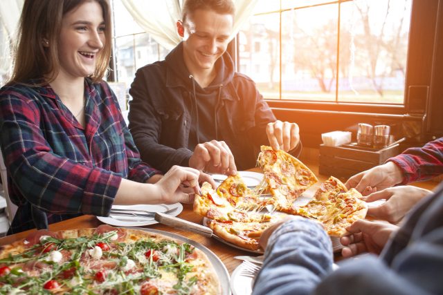 friends of classmates eat pizza in a pizzeria, students at lunch eat fast food Gutscheinbuch.de Schlemmerblock
