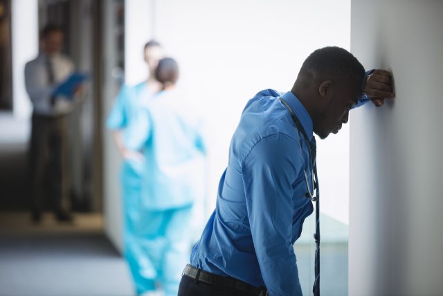 Sad doctor leaning on wall in hospital corridor Medizin ohne Moral