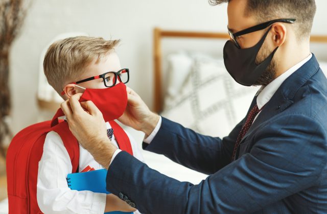 businessman father accompanies his son to school putting on a mask to protect and prevent coronavirus