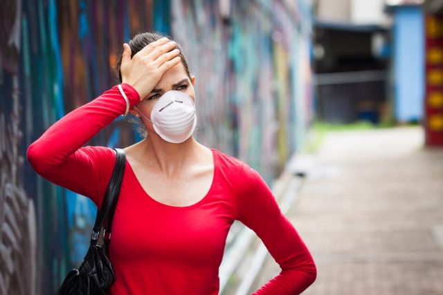 Woman with headache wearing a face mask