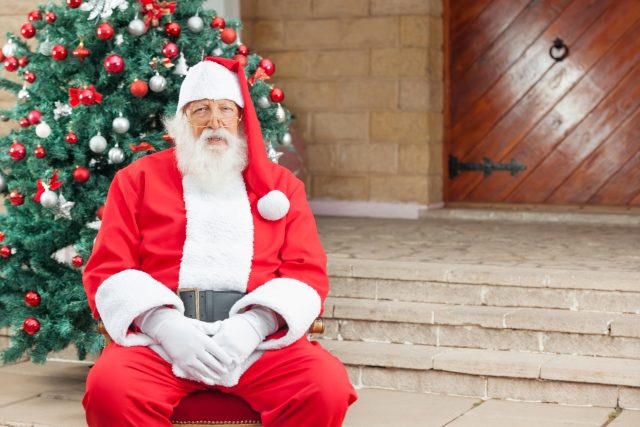 Santa Claus Sitting Against Christmas Tree