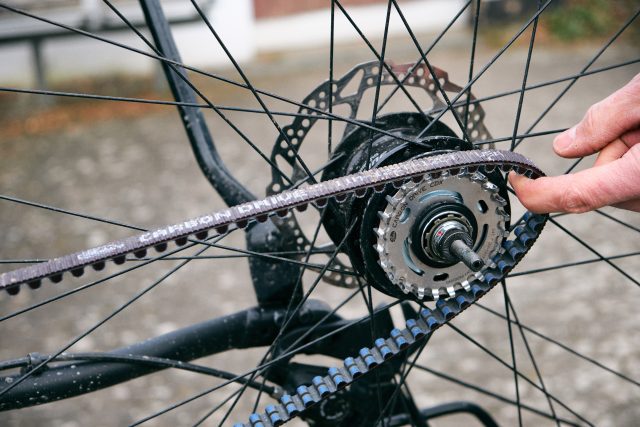 Nach dem Radwechsel wird der Riemen über die Riemenscheiben gezogen.