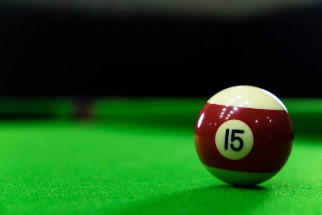 Close-up photos of billiard ball, number 15 and green floor