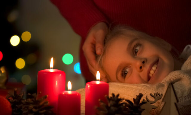 Caring mother comforting her little daughter who looking at Christmas candles