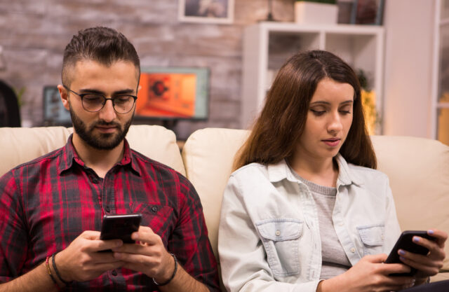 Young couple obsessed with smartphones checking social networks