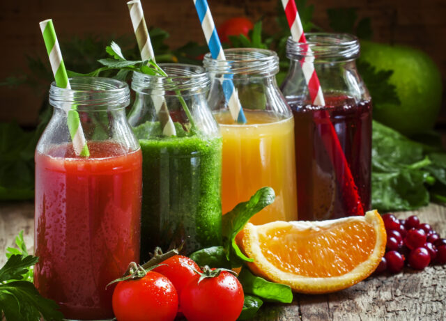 Bottles with fresh juices from fruits and vegetables on an old w