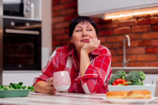 grandma is sitting at the table in the kitchen, drinking coffee