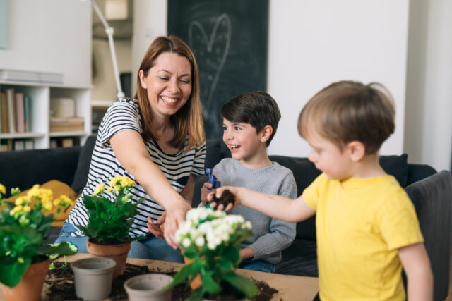 mother with children gardening flowers at home
