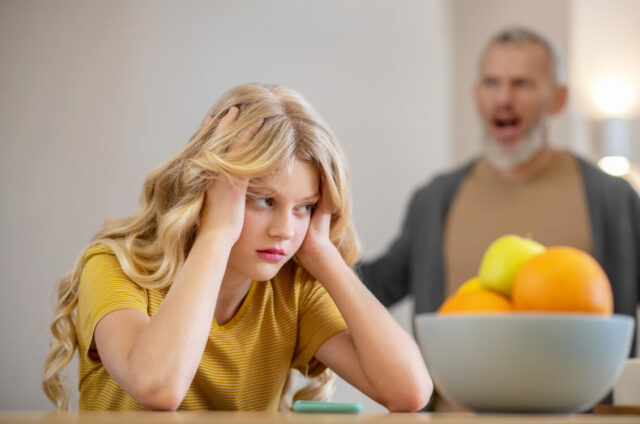 A blonde cute girl feeling frustrated while her father shouting at her