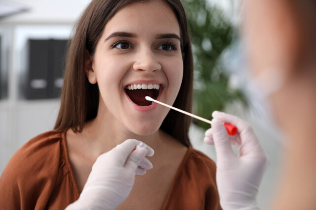 Doctor taking sample for DNA test from woman in clinic