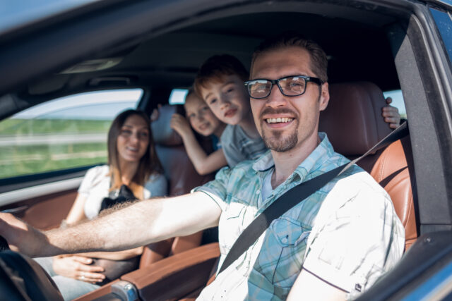 side view.happy father driving a car