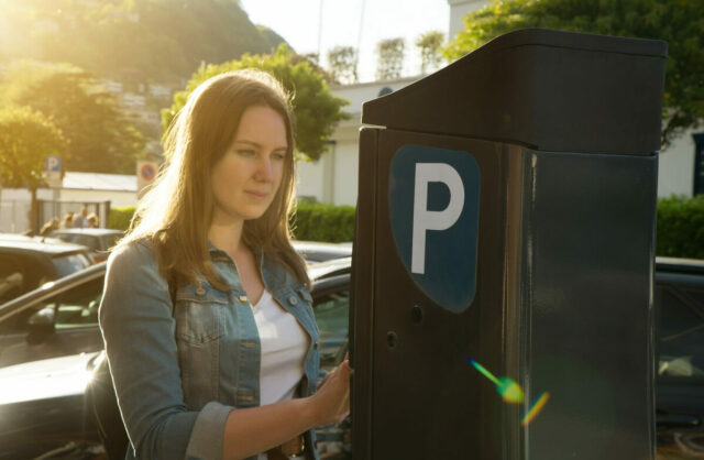 Woman using parking machine on the street.