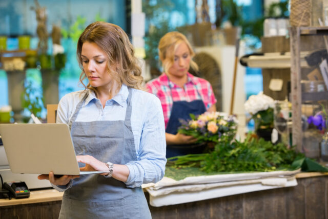 Female Florist Using Laptop In Flower Shop