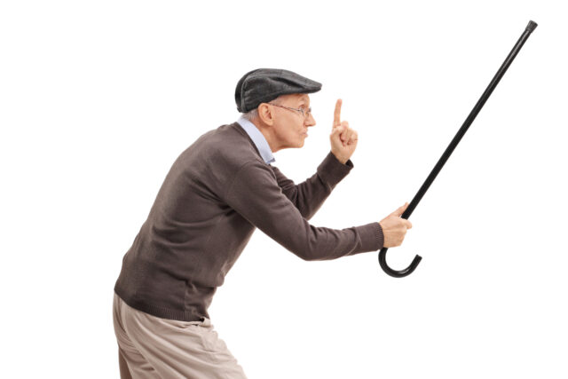 Angry senior holding his cane as a sword and gesturing with his