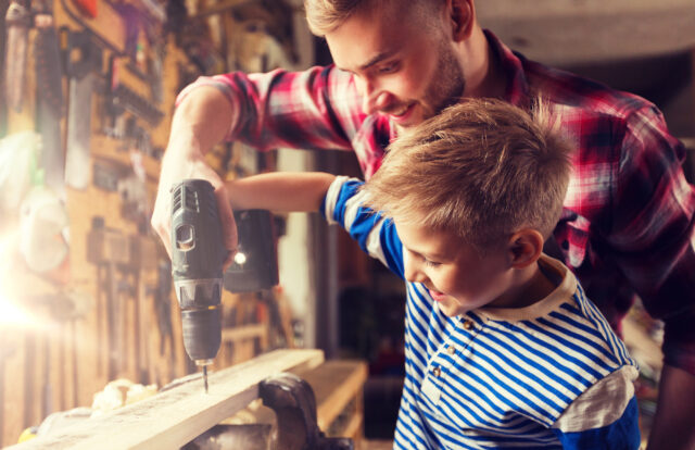 father and son with drill working at workshop