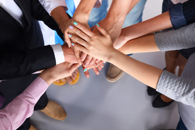 Portrait of people with various occupations putting their hands on top of each other