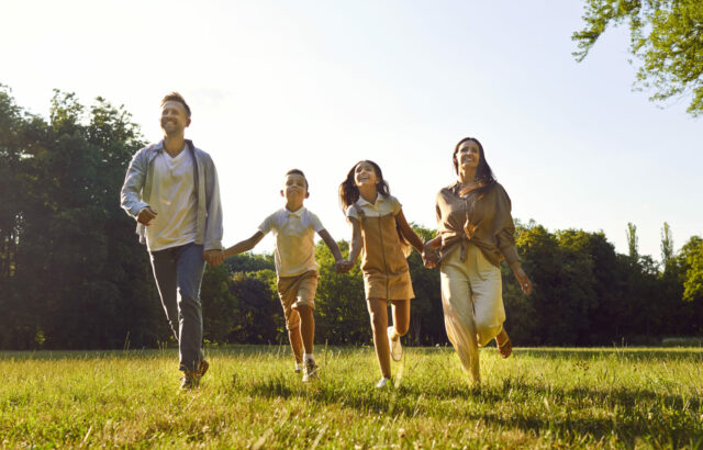 Happy family enjoying leisure time and running together in a beautiful summer park