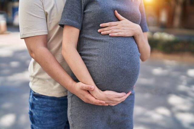 Man and woman couple hugging each other expecting baby at street